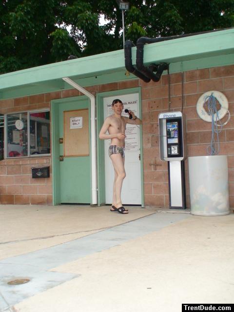 A dude on a pay phone in a swim brief