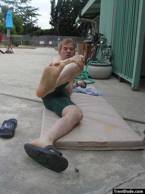 Stretching his foot (nike slippers, nike swim jammer)