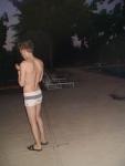 checking his phone before a morning swim (white Speedo Engineered Stripe Square Cut suit) (rear)