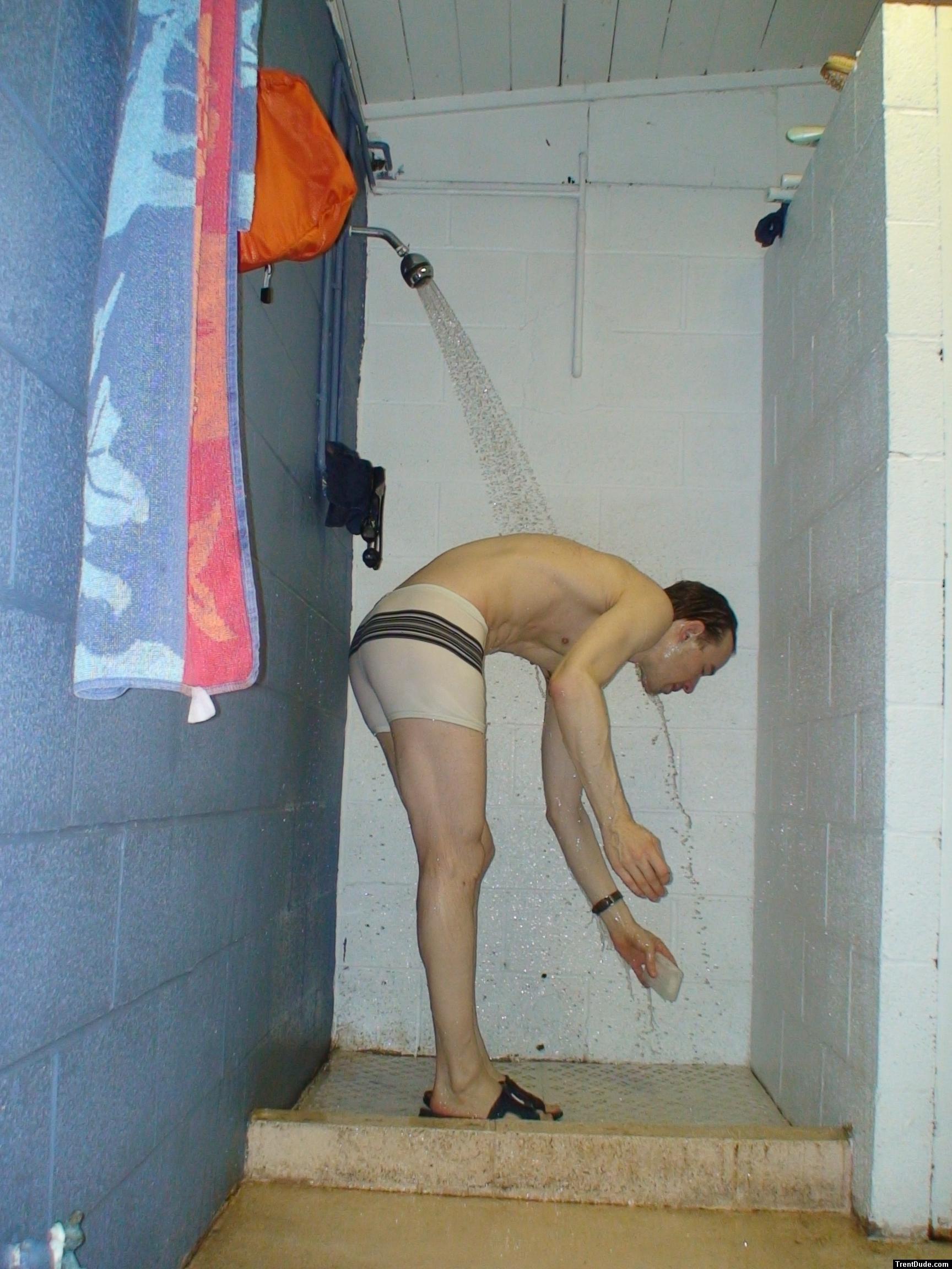 Reaching down for the soap dish in a speedo white suit (rear)