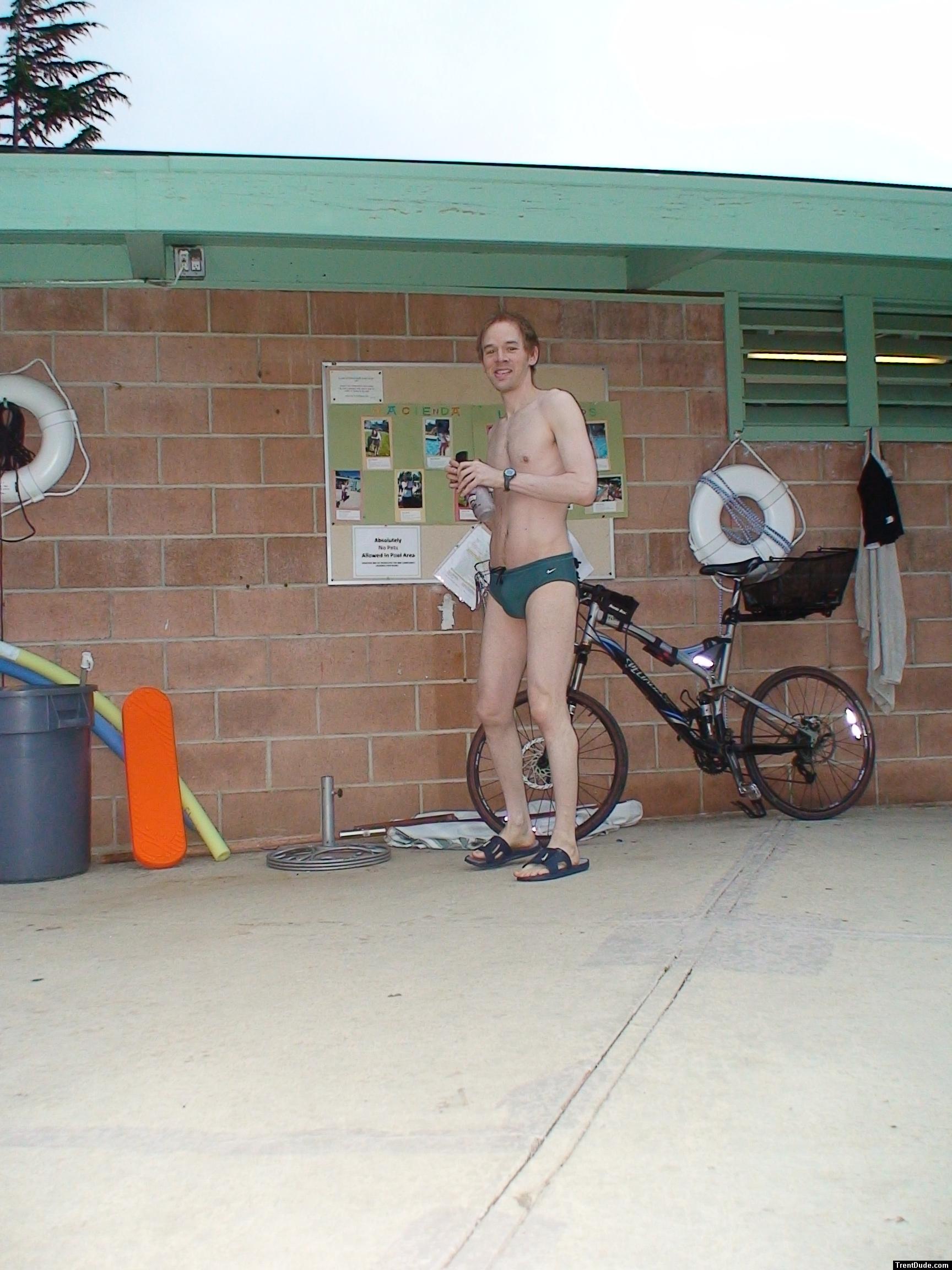Standing near the bike in a Nike speedo
