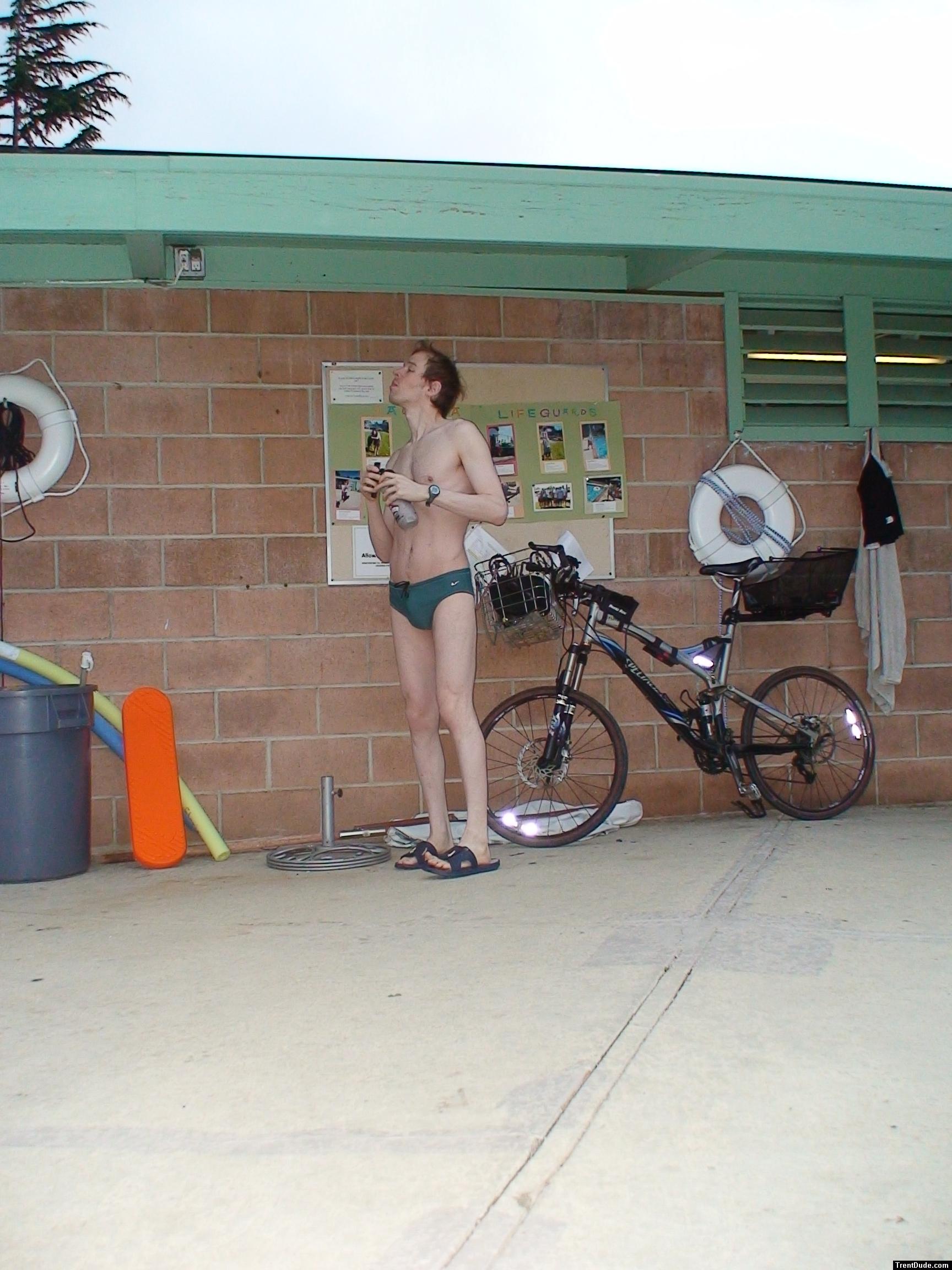Standing near the bike in a Nike speedo