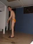 Stretching in the locker room in a yellow speedo