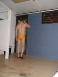 Stretching in the locker room in a yellow speedo