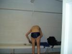 Getting ready to in the locker room wearing a navy blue swim team speedo (rear)