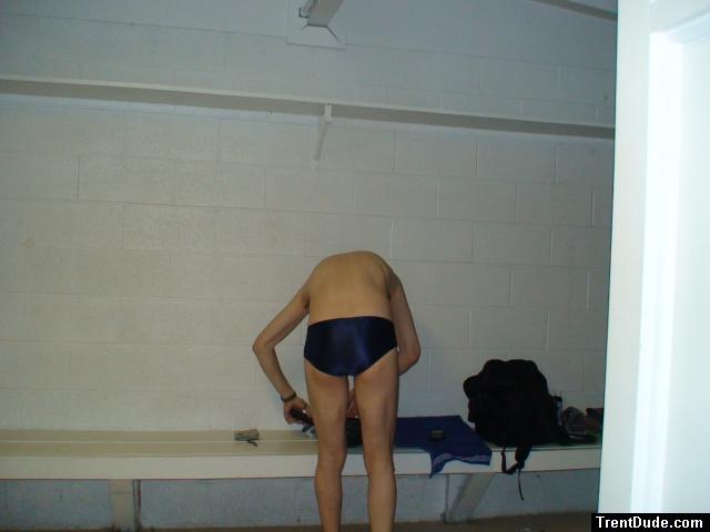 Getting ready to in the locker room wearing a navy blue swim team speedo (rear)