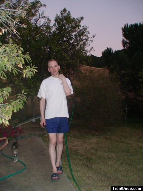 Blue checkered Umbro style soccer nylon shorts, in his backyard with cat