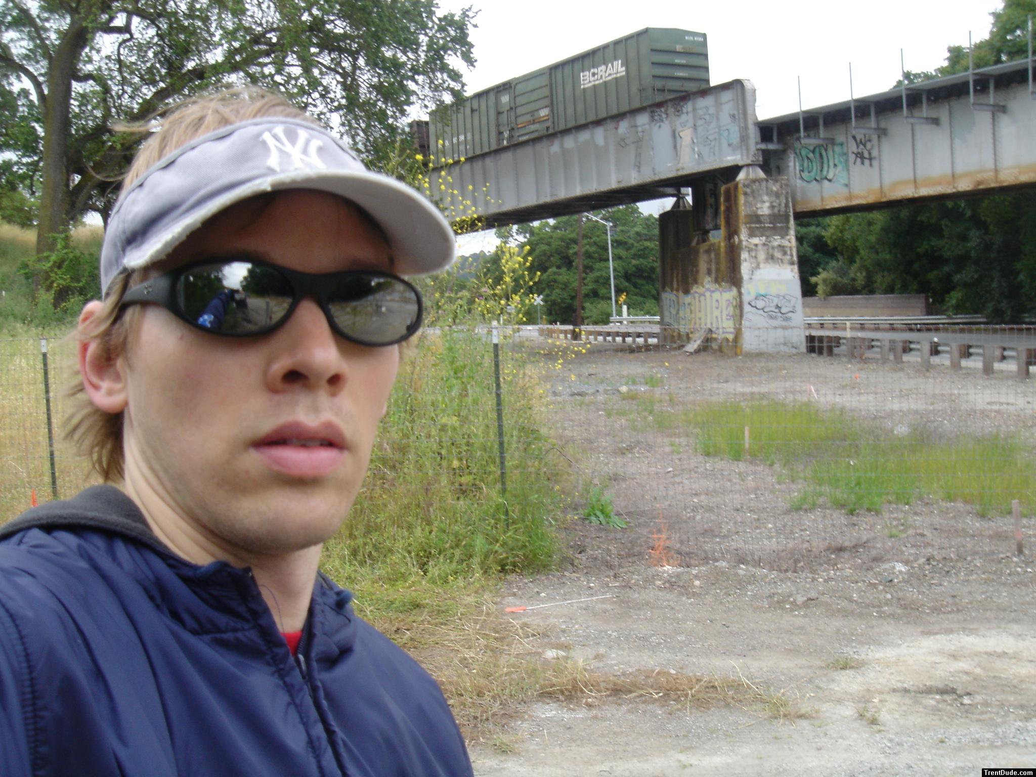Trent near a train with black ray ban sunglasses
