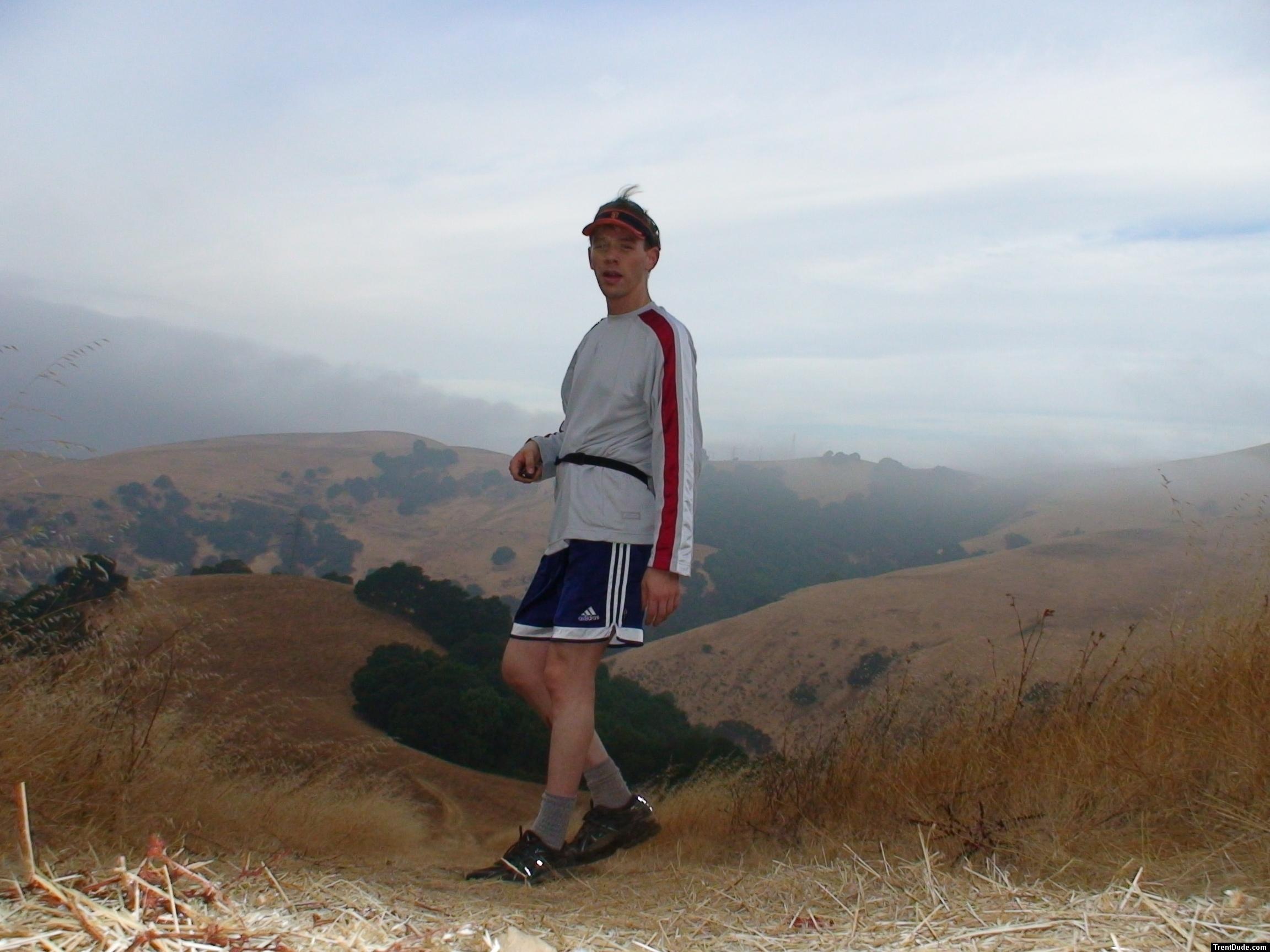 Photoshoot 23 on a mountain top wearubg Blue Addidas shorts, Reebok long sleve shirt