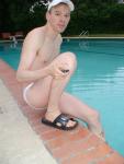 Swimmer in a white speedo and Addidas slippers, resting by the pool