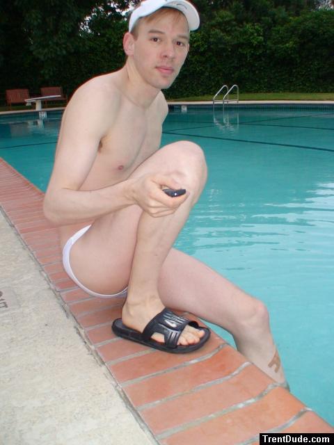 Swimmer in a white speedo and Addidas slippers, resting by the pool
