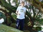 Waterpolo t-shirt, blue sweats, below a Manzanita tree